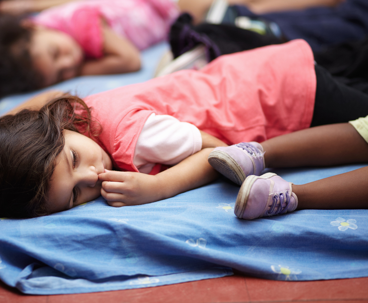 Children lying on mats on the floor.